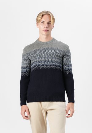 Gebreide trui met een gradient patroon dat overgaat van grijs naar marineblauw, met een zigzagontwerp op de borst en geribbelde manchetten.