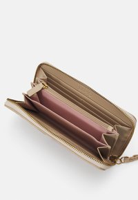 Portafoglio beige con cerniera dorata, l'interno presenta una fodera rosa chiaro, diversi scomparti per carte, una tasca con zip e una tracolla removibile.