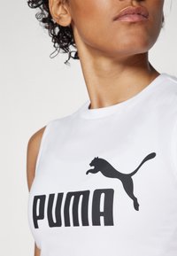 Hvit ermeløs topp med svart Puma-logo og tekst, laget av et glatt, lett stoff med rund halsdesign.