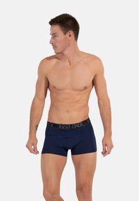 Námořnické modré boxerky s černým elastickým pasem s názvem značky. Materiál vypadá hladce a přiléhavě.