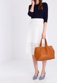 Navy pitkähihaisena paita, valkoinen laserleikattu hame, ruskea nahkakauluspussi ja harmaat korkokengät; sisältää yksinkertaisia muotoja ja tekstuureja koordinoiduissa väreissä.