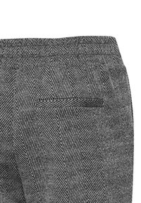 Grau melierte Herringbone-Hose mit einem Bund und einer Gesäßtasche. Das Material wirkt gewebt und hat einen subtilen Glanz.