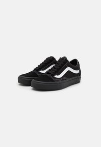 Un paio di sneakers nere basse con strisce bianche sui lati e lacci neri, esposte su uno sfondo bianco.