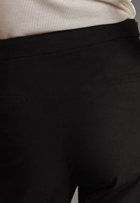 Zwarte, op maat gemaakte broeken met een gladde textuur, voorzien van twee achterzakken en een getailleerde taille, ontworpen voor een slanke uitstraling.