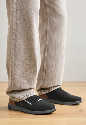 Mustad mustad kingad tekstuurse pealisega, pruunide aktsentidega ja halli tallaga. Kandmisel heledate, vabalt istuvate teksapükstega.