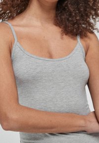 Grå bomulds tanktop med tynde stropper, der har en glat tekstur og en tætsiddende pasform. Enkel, sømløs udskæring uden yderligere pynt.