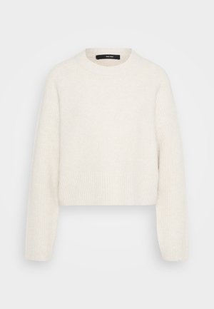Cream-colored ribbed knit sweater with long sleeves and a round neckline, cropped length, and visible brand label inside collar.