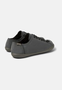 Graue Ledersneaker mit schwarzen Schnürsenkeln, flachem Profil, abgerundeter Zehenpartie, gesteppten Details und einer dünnen Gummisohle. Camper-Logo an der Ferse.