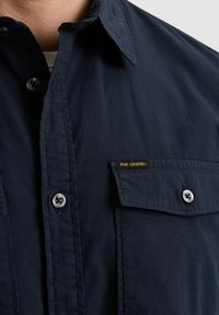 Navy plavi košulja s gumbima i teksturiranom površinom, s džepom na prsima na kojem je oznaka PME Legend i srebrnim gumbima.