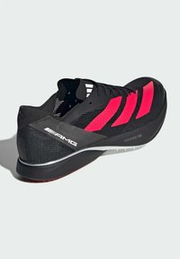 Czarne buty biegowe z różowymi akcentami, siateczkowy wierzch, smukły design, zakrzywiona podeszwa i logo "AMG". Lekka konstrukcja z teksturowaną powierzchnią.