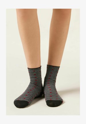 Czarno-białe skarpetki w paski z czerwonymi wzorami serc, długość do połowy łydki, wykonane z miękkiego, elastycznego materiału z czarnym noskiem.