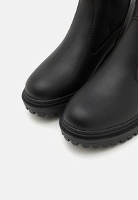 Sorte lær ankle boots med rund tå og teksturert overflate. Har en slitesterk gummisåle med grepklosser og kontrasterende sømmer.