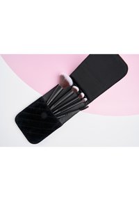 Schwarze Samt-Make-up-Brushcase, die fünf Make-up-Pinsel mit schwarzen Griffen und weichen Borsten hält, in unterschiedlichen Größen und mit einem Spoolie.