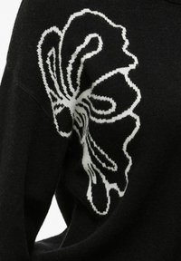 Zwarte gebreide trui met een wit bloemenpatroon op de mouw, met een zachte textuur en een comfortabele pasvorm. Accenten benadrukken de details van het patroon.