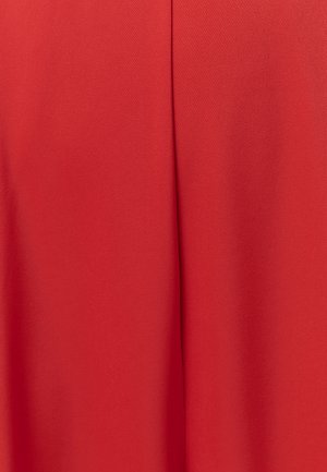 Svijetlo crvena tkanina s vertikalnim šavom i blagim teksturnim detaljem, prikazujući glatko padajući nabor i živu boju.