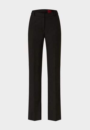 Pantaloni neri sartoriali con gamba dritta e passanti per cintura, caratterizzati da una piega sottile nella parte anteriore e un'etichetta visibile all'interno della cintura.