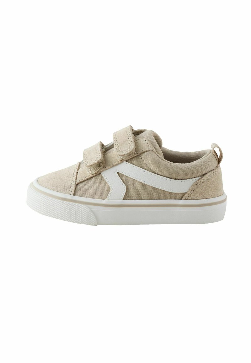 Zapatillas de lona beige con tiras de velcro blancas y un detalle en zigzag blanco. Punta redondeada, suela texturizada y una lengüeta trasera para facilitar el calzado.