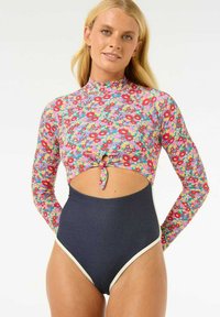 Haut de bain à manches longues avec des fleurs et une découpe en trou de serrure, associé à un bas taille haute navy avec des accents blancs. Design lumineux et coloré.