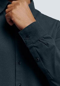 Donkerblauwe overhemd met knopen van een gestructureerde stof, voorzien van een gestructureerde kraag, knoopsluiting en op maat gemaakte manchetten.