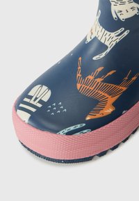 Bota de chuva de borracha com fundo azul-marinho e padrões coloridos de animais. Sola e biqueira texturizadas em rosa. Design durável e à prova d'água.