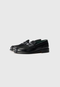 Loafers din piele neagră cu un finisaj neted, având un vârf cusut și o curea decorativă în partea din față, așezați pe un toc joasă, stratificat.