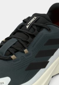 Μαύρο ελαφρύ αθλητικό παπούτσι με υφασματώδη συνθετικό επάνω μέρος, κορδόνια και τρεις σκούρες ρίγες στο πλάι, με λευκή σόλα.