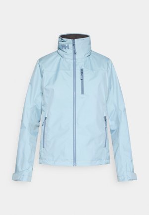Veste imperméable bleu clair avec un col montant, une fermeture éclair frontale et deux poches latérales. Texture lisse ; logo présent sur le col.