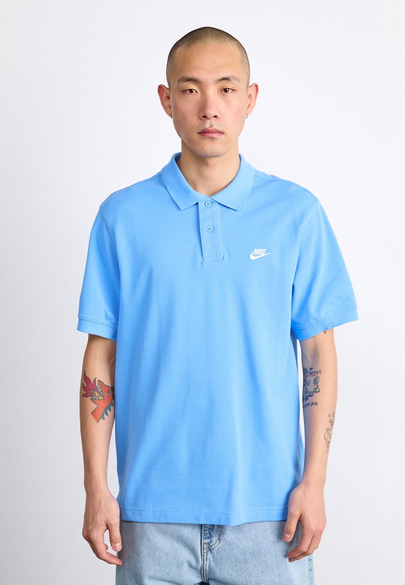 Svetlomodrá polo košela vyrobená z bavlny, s klasickým golierom, krátkymi rukávmi a malým bielym logom Nike na hrudi.