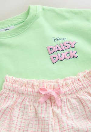 Sweatshirt vert clair avec le texte "Daisy Duck" en rose. Shorts blancs avec un motif quadrillé rose et un nœud rose à la ceinture.