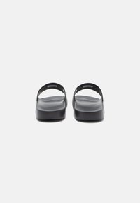 Black sandals with two curved straps, flat soles, and a smooth texture. The design is minimalistic with no visible patterns or accents.
