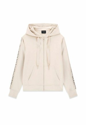 Felpa con cappuccio beige con zip integrale, tasche frontali, cappuccio con coulisse e testo nero stampato su entrambe le maniche.