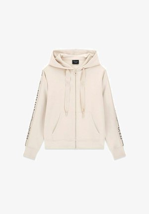 Felpa con cappuccio beige con zip integrale, tasche frontali, cappuccio con coulisse e testo nero stampato su entrambe le maniche.