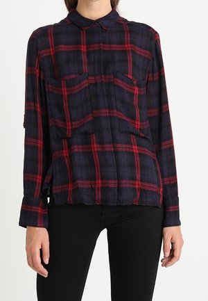 Chemise à manches longues à carreaux avec un motif vichy bleu marine et rouge, deux poches poitrine, un col boutonné et un tissu texturé.