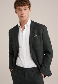 Ogļu dūmu raibajā uzvalkā ar izgrieztām atlokām, ar vienu pogu un zem tā valkātu baltu krekli. Iekļauts rakstains kabatas kvadrāts.