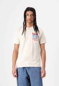 Cream cotton t-shirt with short sleeves, featuring multicolored graphic print reading "OBEY MAKE ART NOT WAR" on the left chest area.