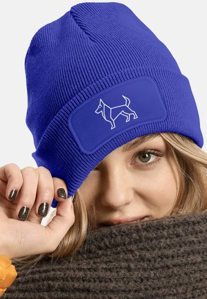 Blue knitted beanie hat with a textured finish, featuring a rectangular patch with a white geometric dog design.