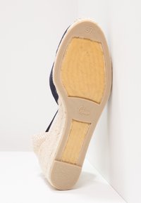 Sandale compensée en tissu marine avec un talon recouvert de jute, semelle en caoutchouc, taille 37, et détails texturés sur le dessous. Fabriqué en Espagne.