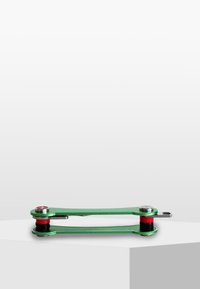 Grön metall multifunktionell verktyg med en platt design, utrustad med silverdetaljer och röda accenter. Slät yta med en kompakt, avlång form.