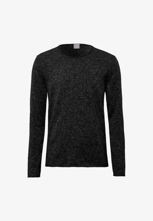 Pantaloni in misto lana grigia e un maglione nero a maniche lunghe, indossati con scarpe nere lucide, in piedi contro uno sfondo bianco.