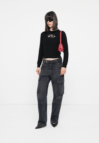 Svart kortermet genser med oval skjæring; høyt liv grå cargo bukser med lommer; rød mini handbag; spisse svarte hæler; solbriller.