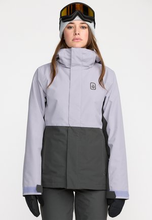 Veste de neige lilas claire avec une partie inférieure gris foncé, col haut, poignets réglables et patch de logo. Présente un design superposé.