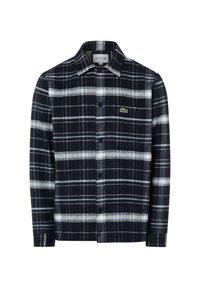 Chemise en flanelle de coton à carreaux bleu marine et blanc, avec un col, une fermeture à boutons sur le devant, et un petit logo vert sur la poche poitrine gauche.