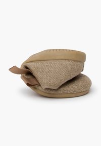 Pantoufles en tissu beige avec une texture douce, semelle en caoutchouc, design flexible et une sangle brune en boucle pour un enfilage et un retrait faciles.