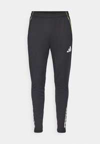 Zwarte sportbroek met een slim fit, voorzien van een wit logo, groene accenten en witte strepen aan de zijkanten langs de onderbenen. Zachte stoftextuur.