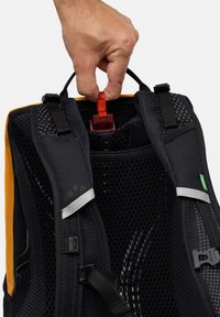 Zaino nero e arancione con schienale in rete, spallacci regolabili e una clip rossa. Presenta un'etichetta con logo e dettagli riflettenti.