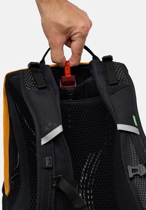 Zaino nero e arancione con schienale in rete, spallacci regolabili e una clip rossa. Presenta un'etichetta con logo e dettagli riflettenti.