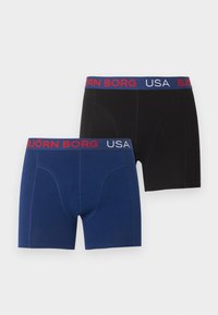 Δύο εσώρουχα boxer Björn Borg σε μαύρο και μπλε χρώμα, το καθένα με μπλε ζώνη μέσης με κόκκινο και λευκό κείμενο "BJÖRN BORG USA".