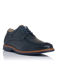 Zapato de cuero azul marino con cordones, paneles laterales perforados, suela marrón en contraste y cordones azules. Presenta una textura suave y punta redonda.