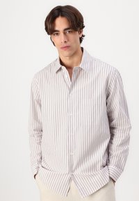 Chemise à rayures aux teintes claires, avec des lignes verticales violettes et blanches, col, manches longues et une poche poitrine.