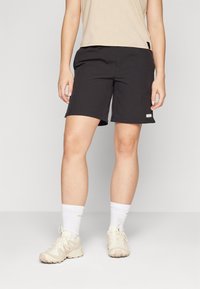 Black shorts with a smooth, lightweight fabric. Features a subtle logo on the side, paired with light-colored athletic shoes and white socks.